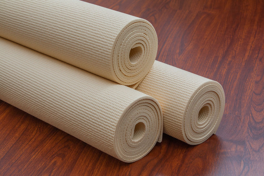 two rolls of beige yoga mat on a wooden floor