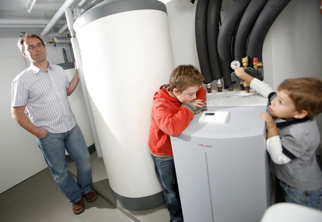 a man and two children standing next to a water heater