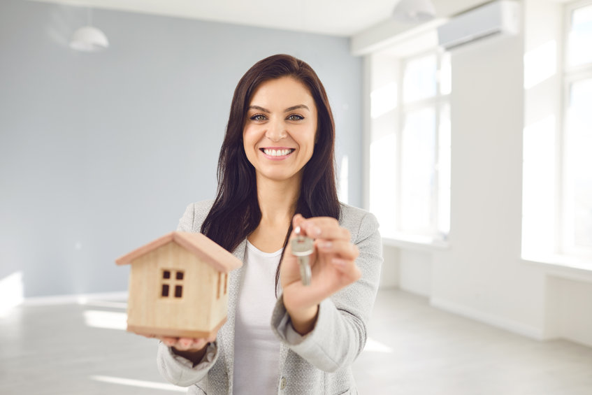 a woman holding a house key and smiling
