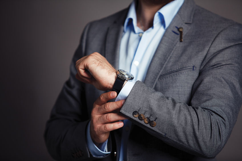 a man in a suit is adjusting his watch