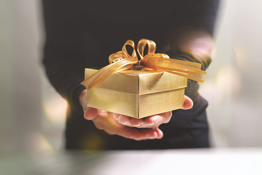 a person holding a golden gift box with a ribbon