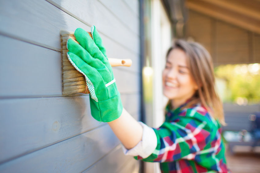 a woman wearing gloves and a green glove is painting a house