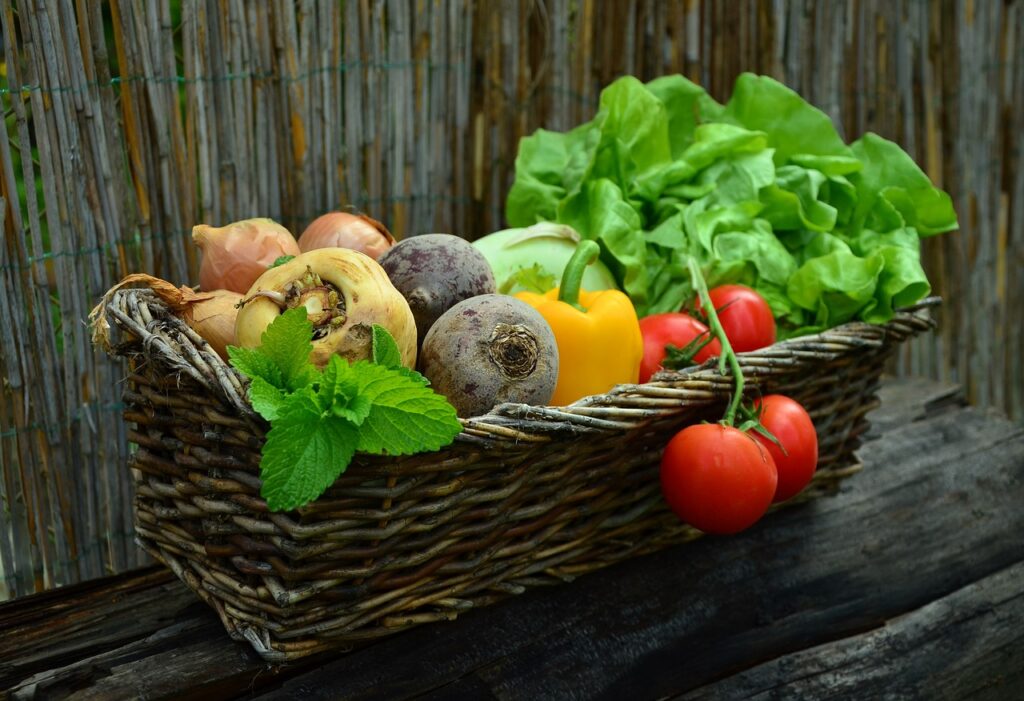 a basket with vegetables and herbs on a wooden table