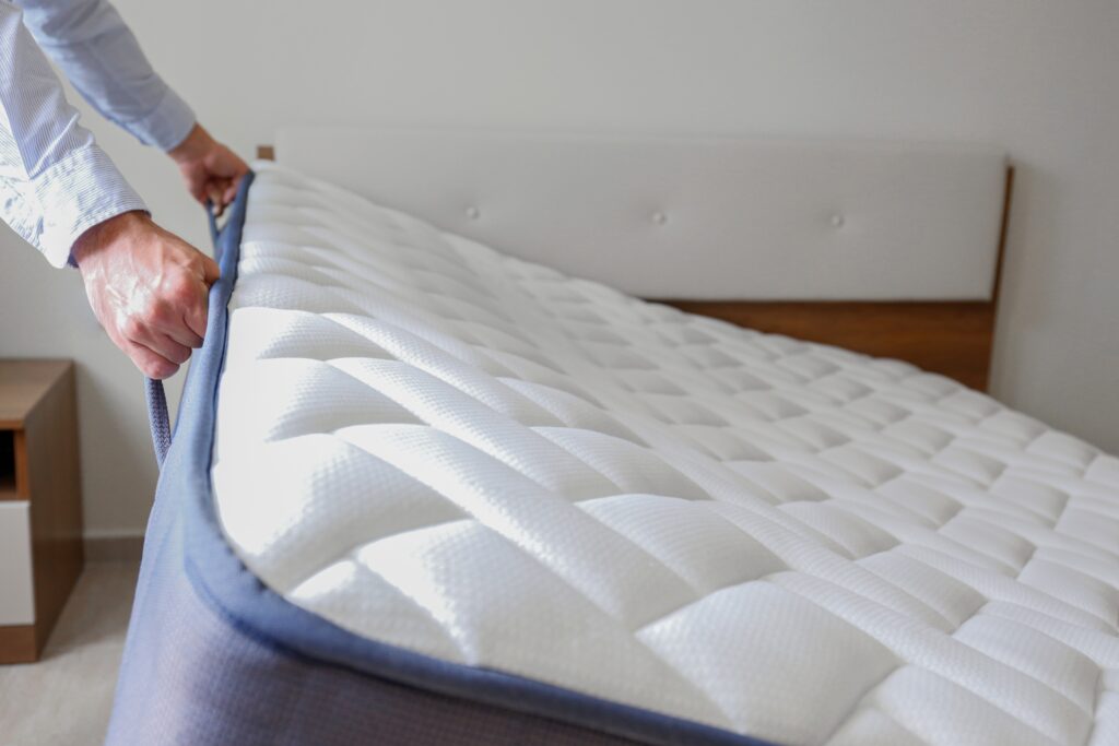 a man is putting a mattress on a bed