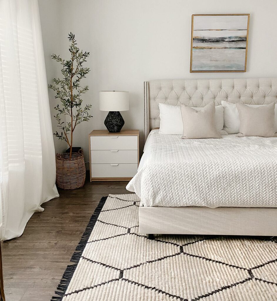 a clean bedroom with a white bed and black and white rug