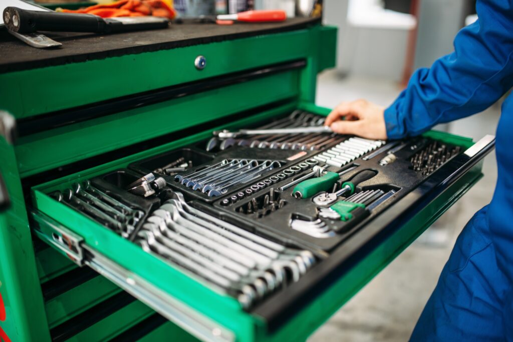 Un mécanicien ouvre une boîte à outils bien organisée contenant divers clés et outillage.