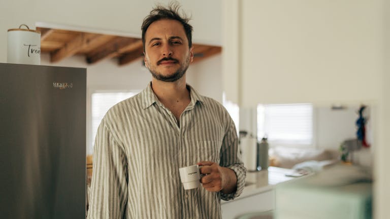 Man enjoying a casual morning coffee in a cozy kitchen setting.