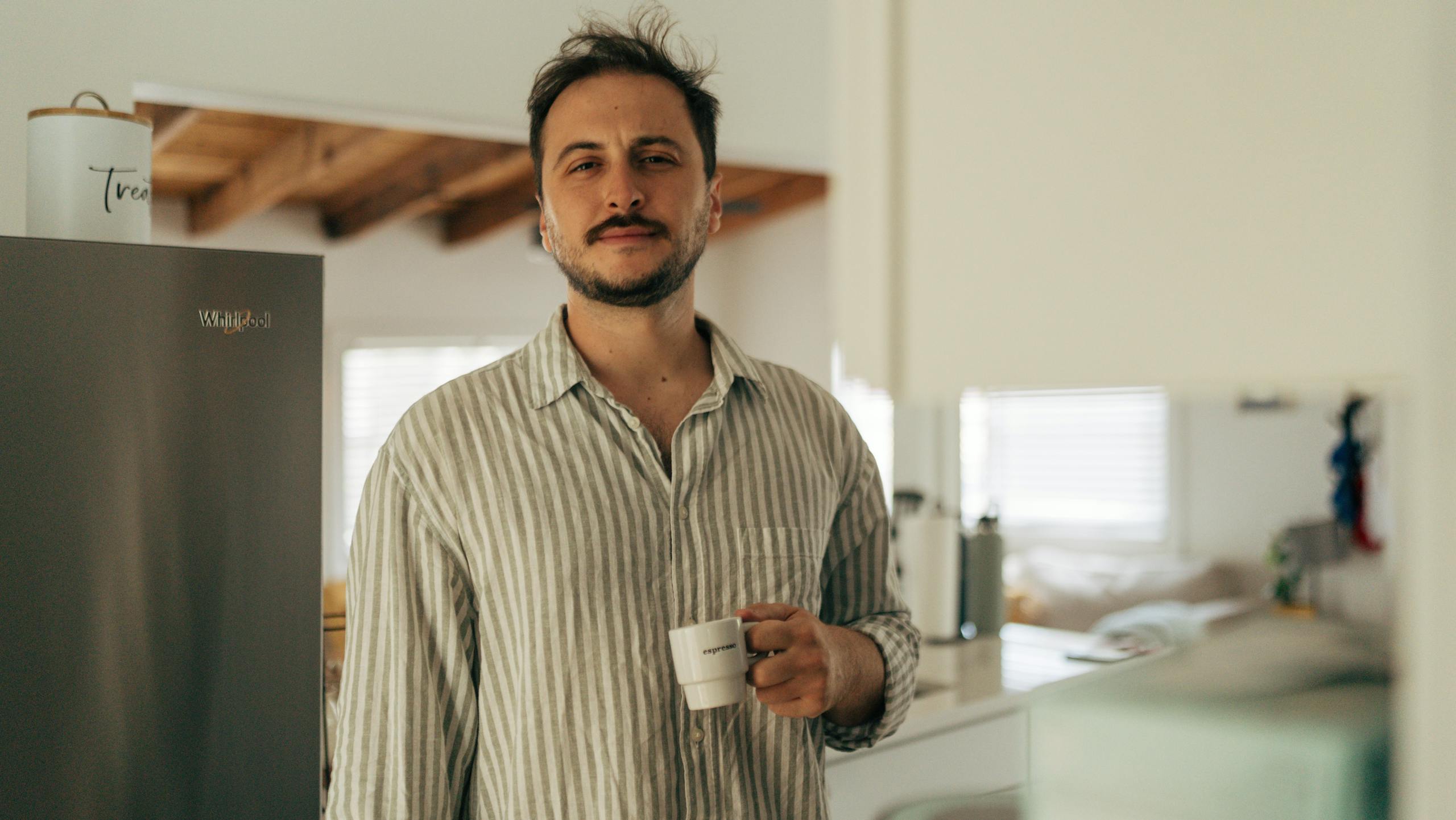 Man enjoying a casual morning coffee in a cozy kitchen setting.