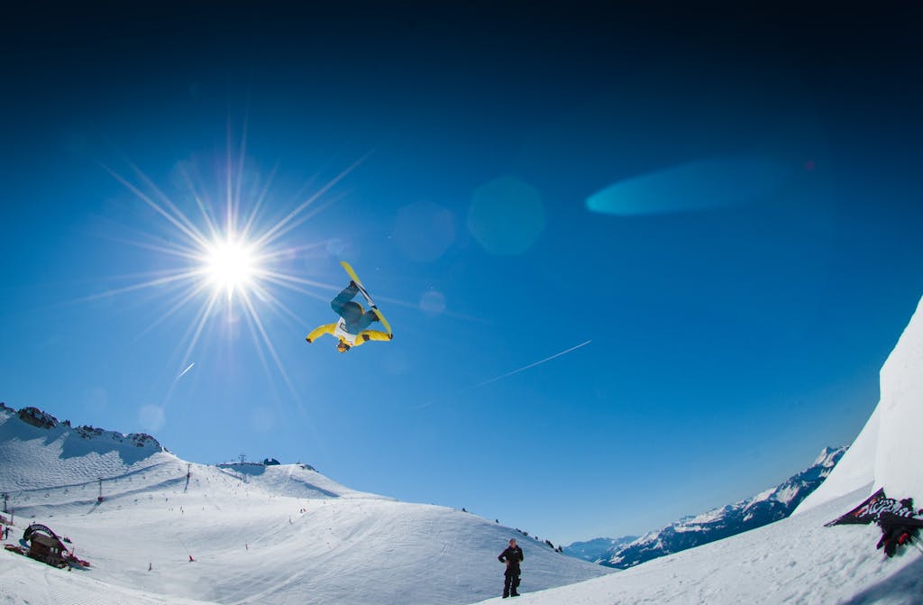 Snowboarder executing a freestyle trick in the sunny winter Alps.